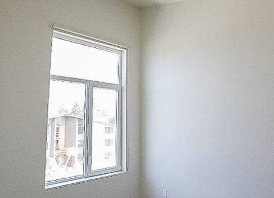 A room with a window and a view of a building outside.