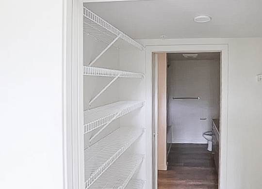 A white pantry with a doorway leading to a bathroom.