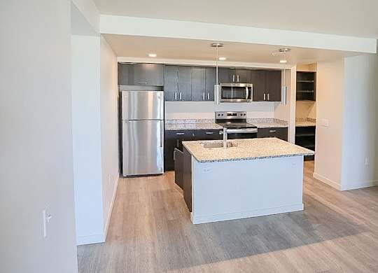 A modern kitchen with a stainless steel refrigerator and a granite countertop.