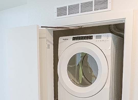 A white dryer is stacked on top of a white washer.