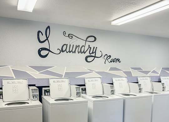 A laundry room with washing machines and a wall sign.