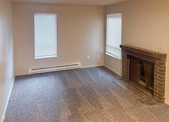 A room with a fireplace and two windows.