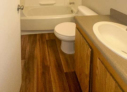A white toilet sits in a bathroom next to a bathtub.