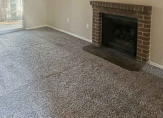 A room with a fireplace and carpeted floor.