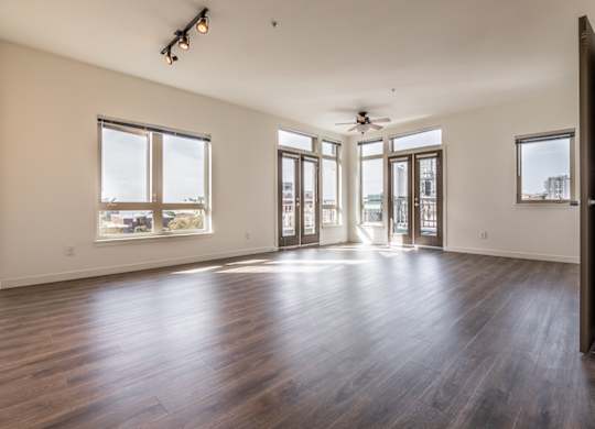 A spacious room with wooden floors and large windows.