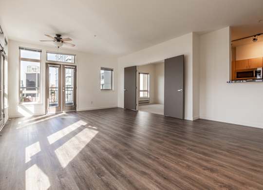 A spacious room with wooden floors and a ceiling fan.