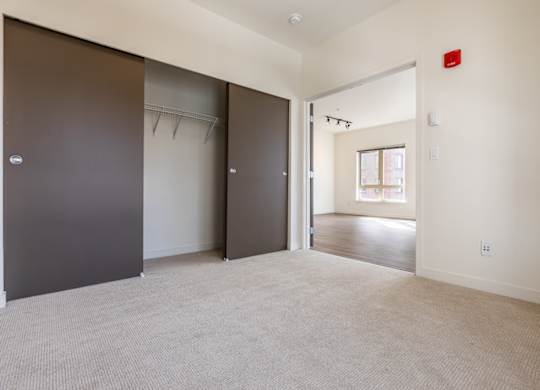 A room with a carpeted floor and a door on the left.