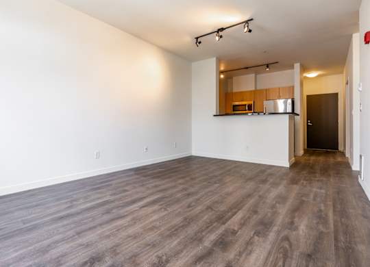 A spacious room with wooden flooring and a small kitchenette in the corner.