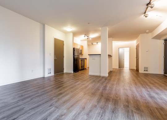 A spacious room with wooden floors and white walls.