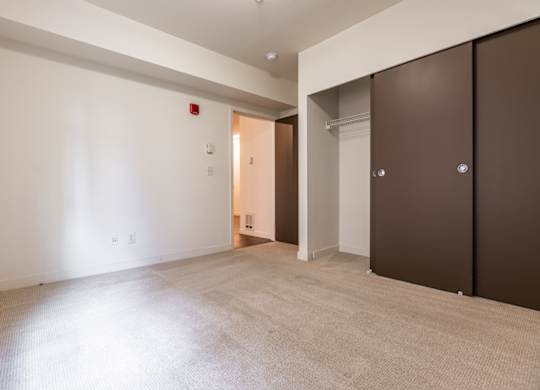 A room with a carpeted floor and a doorway leading to another room.
