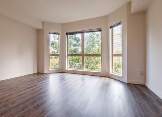 A room with wooden floors and two windows.