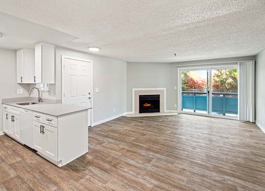 A kitchen with a fireplace and a view of a balcony.