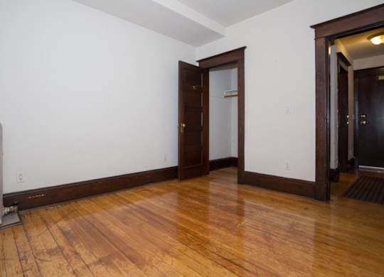 A room with wooden floors and a white wall with a door.