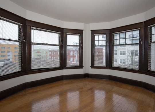 A room with wooden floors and three windows.