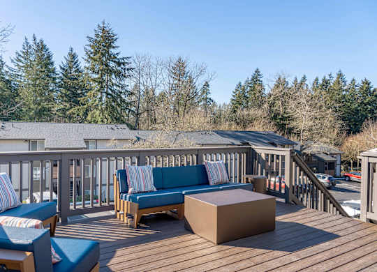 A wooden deck with blue cushions and a bench.