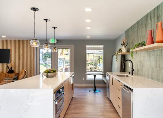 A kitchen with a white counter top and wooden floors.