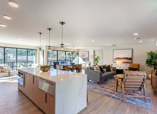 A modern kitchen with a large island and a living area with a couch and chairs.