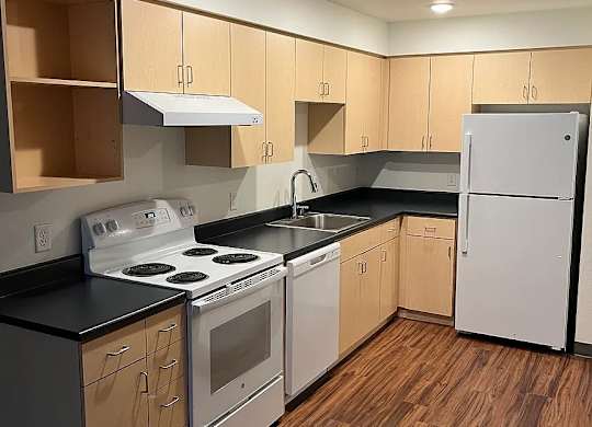 A kitchen with wooden floors and white appliances.