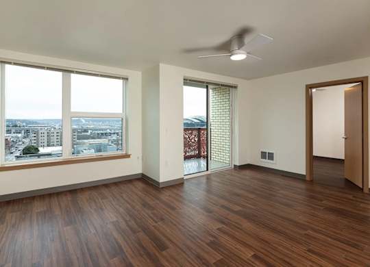 A room with a ceiling fan and a view of the city.