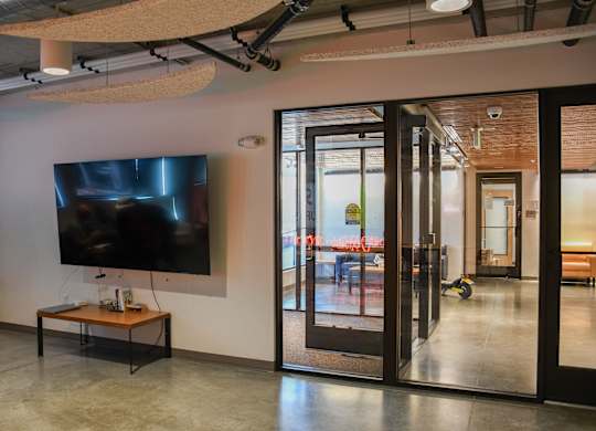 A modern room with a flat screen TV mounted on the wall and a glass door leading to a balcony.