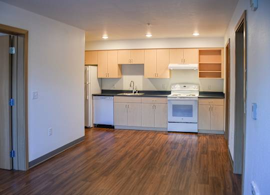 A kitchen with wooden floors and white appliances.