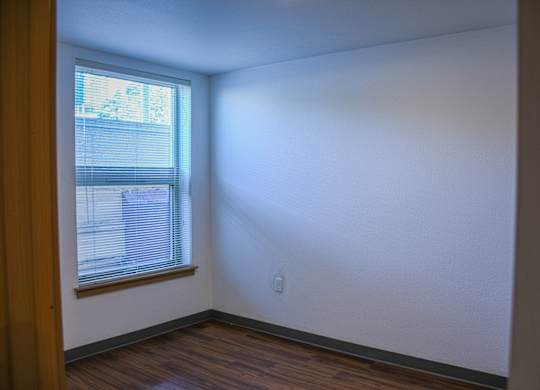 A room with a window and wooden floors.