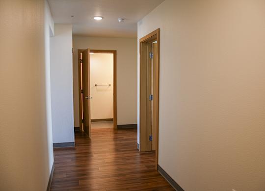 A hallway with two doors and a wooden floor.