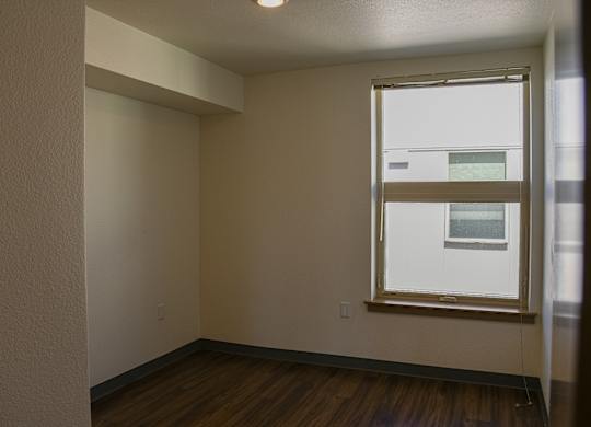 A room with a window and wooden floors.