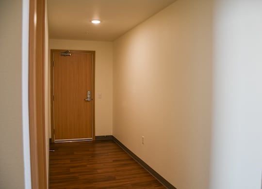 A hallway with a wooden door and a light on the ceiling.