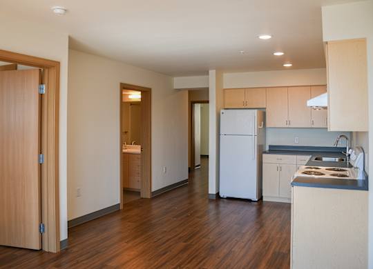 A kitchen with a white fridge and wooden floors.