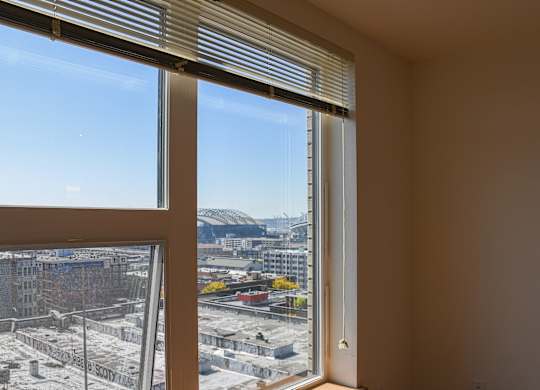 A view of a construction site through a window with blinds.