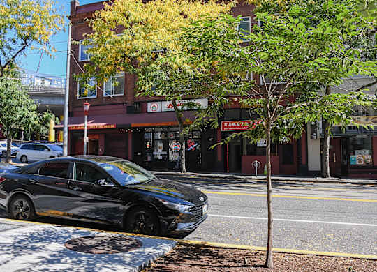 A black car is parked on the side of the street.
