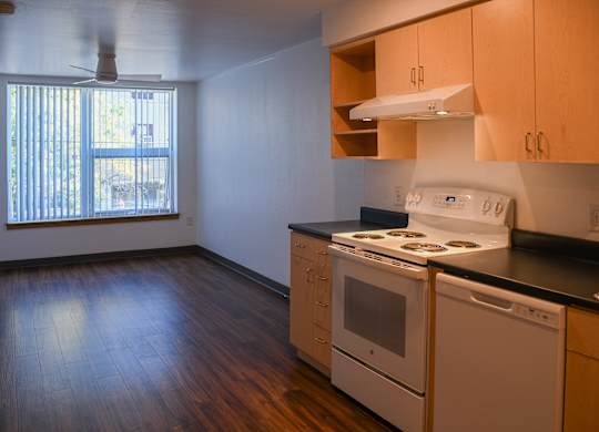 A kitchen with white appliances and wooden floors.