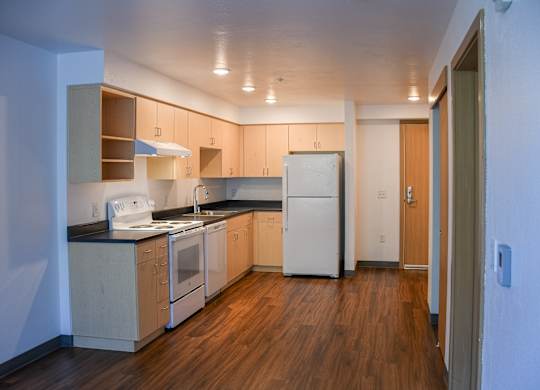 A kitchen with wooden floors and white appliances.