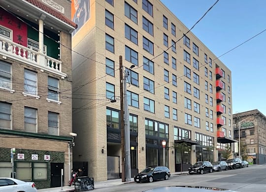 A modern building with a mural on the side is situated between two older buildings.