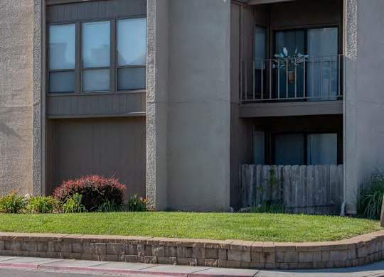 A grey building with a balcony and a garage door.