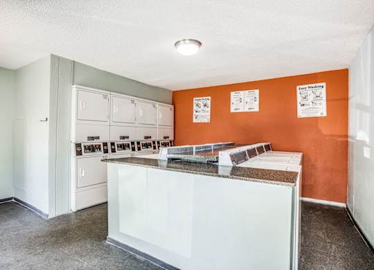 A white counter with orange walls and a white door.