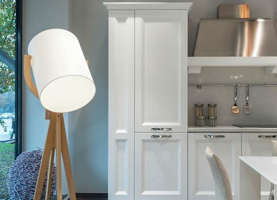 A white lamp stands next to a white cabinet in a kitchen.