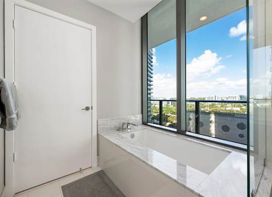 A bathroom with a large window overlooking a cityscape.