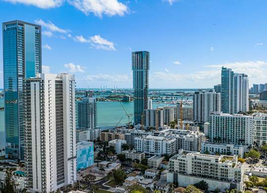 A cityscape with tall buildings and a body of water in the distance.