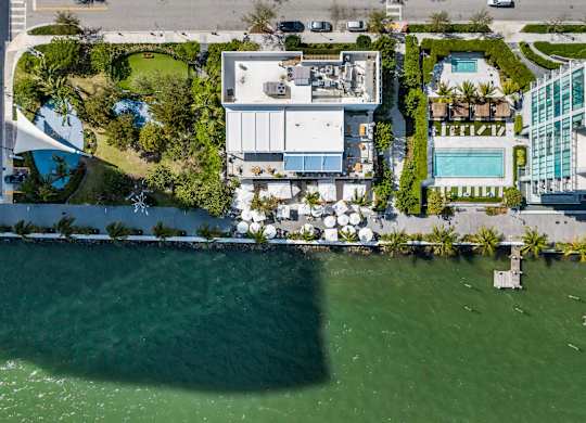 A large white building sits on the edge of a body of water.