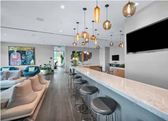A modern kitchen with a bar area and a television mounted on the wall.