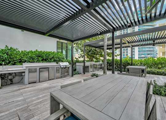 A wooden deck with a table and chairs under a roof.