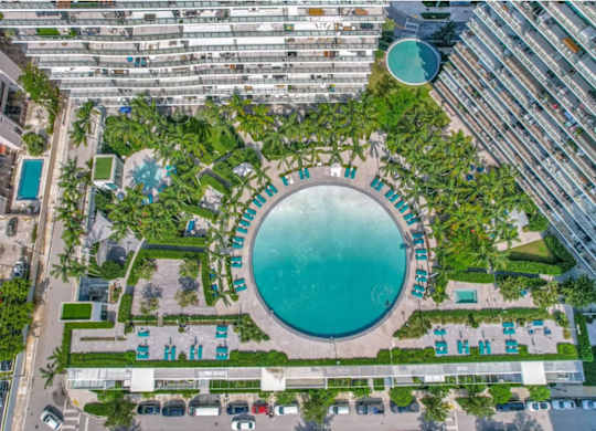 A large round pool surrounded by trees and buildings.