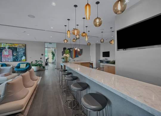 A modern bar area with a long counter and stools.