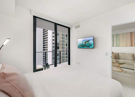 A modern living room with a large window and a flat screen TV mounted on the wall.