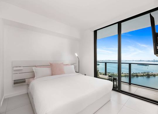 A bedroom with a large bed and a view of the water.