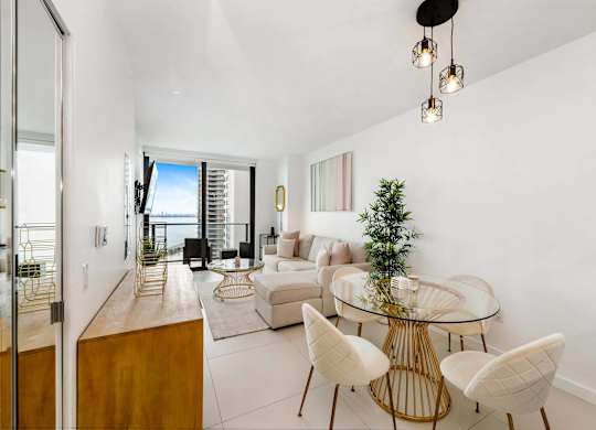 A modern living room with a glass table and white chairs.