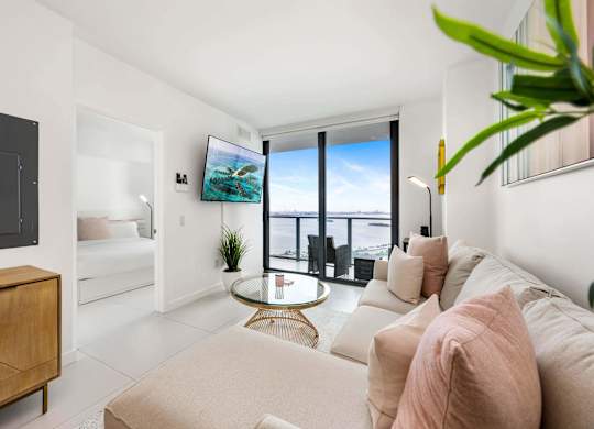 A living room with a white couch and a glass table.