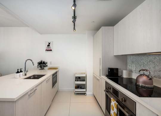 A modern kitchen with a white countertop and stainless steel appliances.